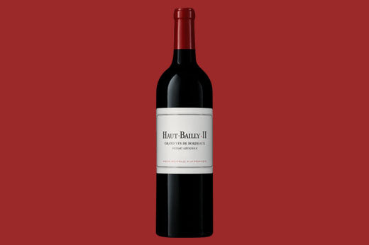 Bottle of 2018 Haut-Bailly II Bordeaux, plain white label, against a deep red background