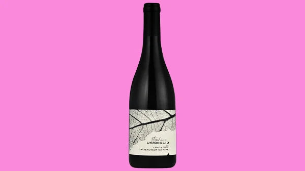 Bottle of red wine with a white label showing a leaf skeleton, on a bright pink background