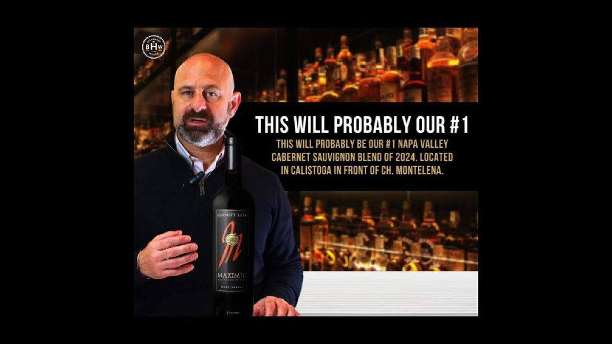 Man holding a dark-labeled bottle of Napa Valley Cabernet Sauvignon at a bar
