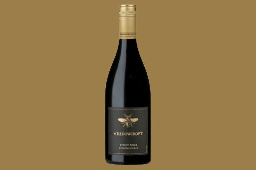 Bottle of 2019 Meadowcroft Pinot Noir, Sonoma Coast, black label with a gold bee, tan background