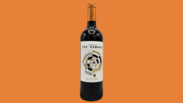 Bottle of Chateau Puy d'Amour Bordeaux, cream label with a black and gold circular design