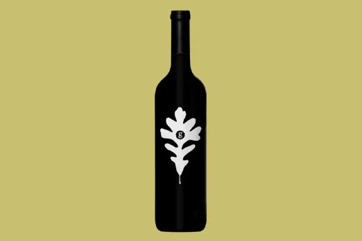 Dark bottle with a white oak leaf emblem on the label, on a khaki background