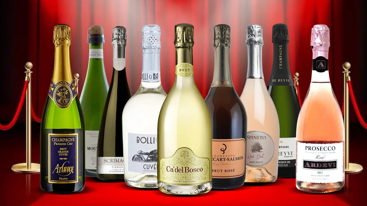 Nine sparkling wine and Champagne bottles lined up on a red carpet behind a velvet rope