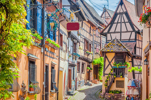Narrow street of half-timbered houses with flower boxes and hanging signs in an Alsace village