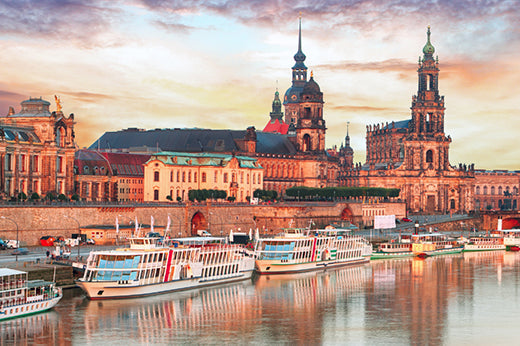 Baroque riverfront skyline in Germany at sunset with tour boats moored along the river