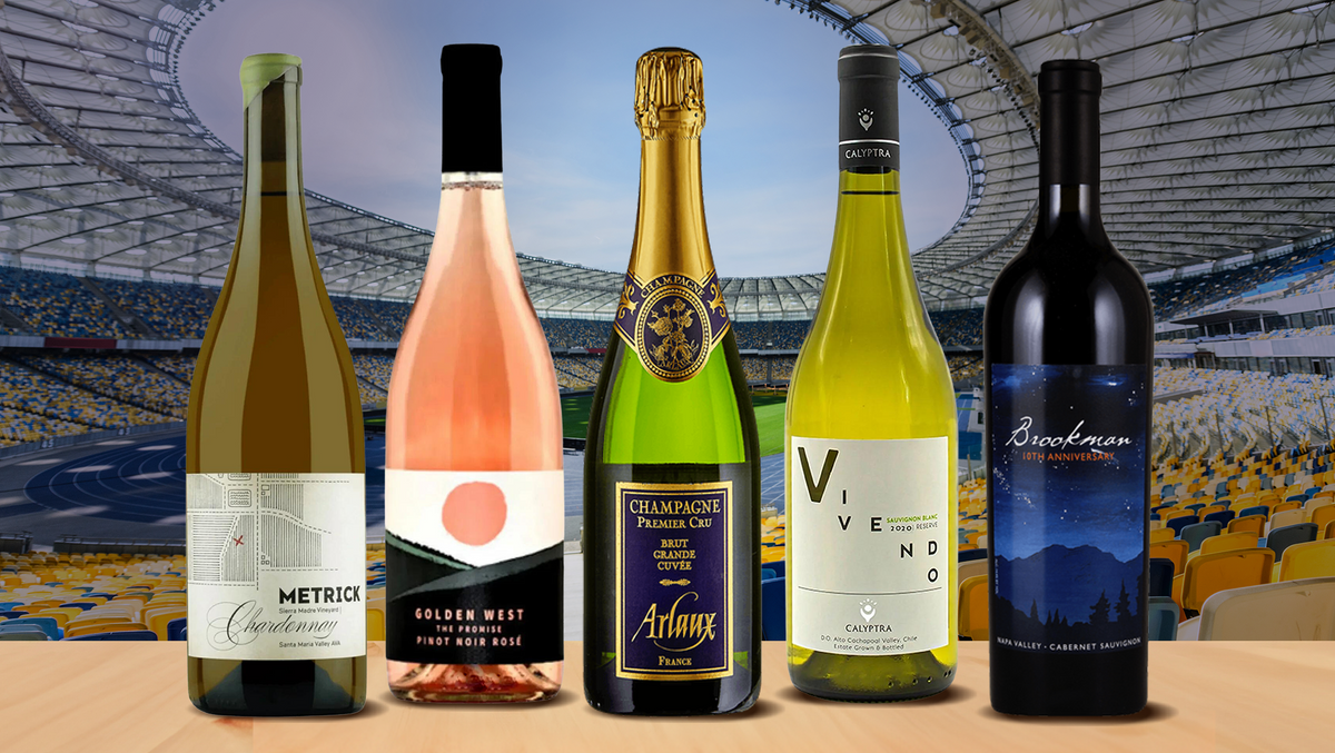 Five bottles of white, rose, Champagne and red wine standing in front of an empty stadium
