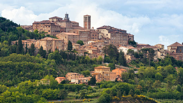 Hilltop town of Montepulciano with stone towers and buildings above wooded Tuscan hills