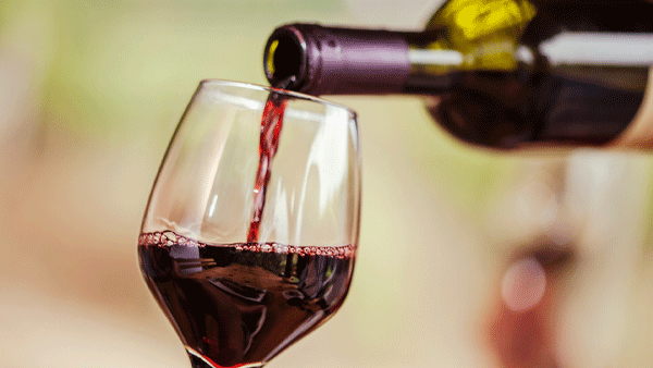 Red wine being poured from a bottle into a stemmed glass