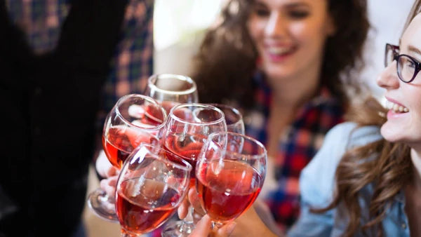 Group of friends clinking glasses of rosé wine together outdoors