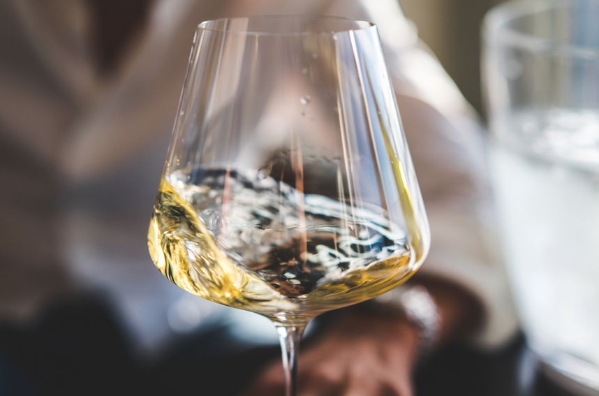 White wine swirling inside a stemmed glass, shot close up against a blurred background