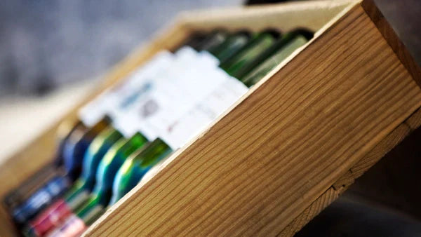 Open wooden wine crate holding several bottles on their sides, close-up