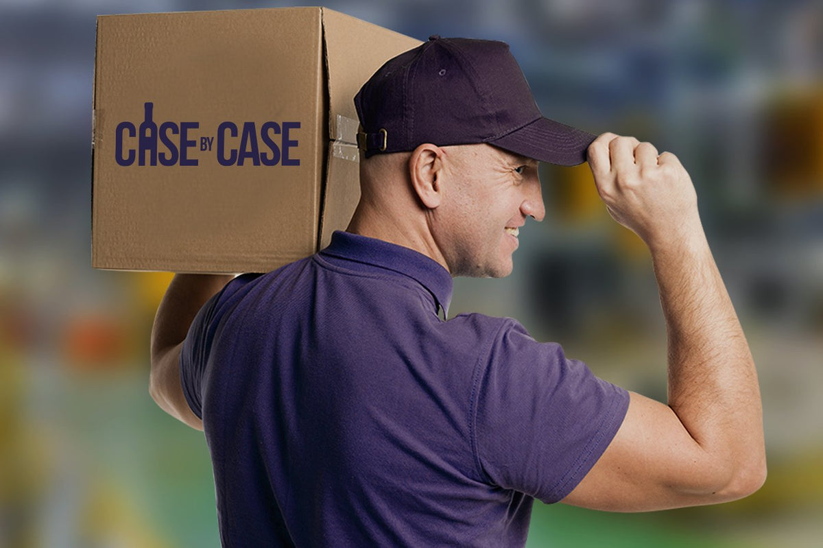 Man in a purple polo and cap carrying a cardboard box marked "Case by Case" on his shoulder