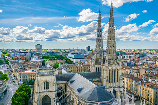 Twin Gothic cathedral spires rising above the rooftops of Bordeaux under a cloudy sky