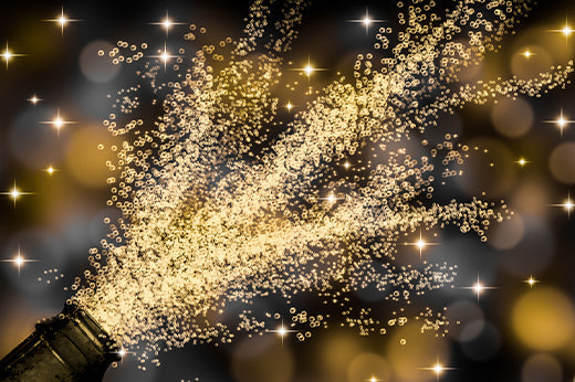 Sparkling wine bottle neck spraying a burst of golden sparkles against a dark background