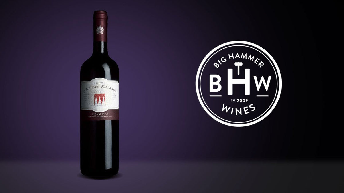Bottle of red wine with a cream label and red crest, beside the Big Hammer Wines logo