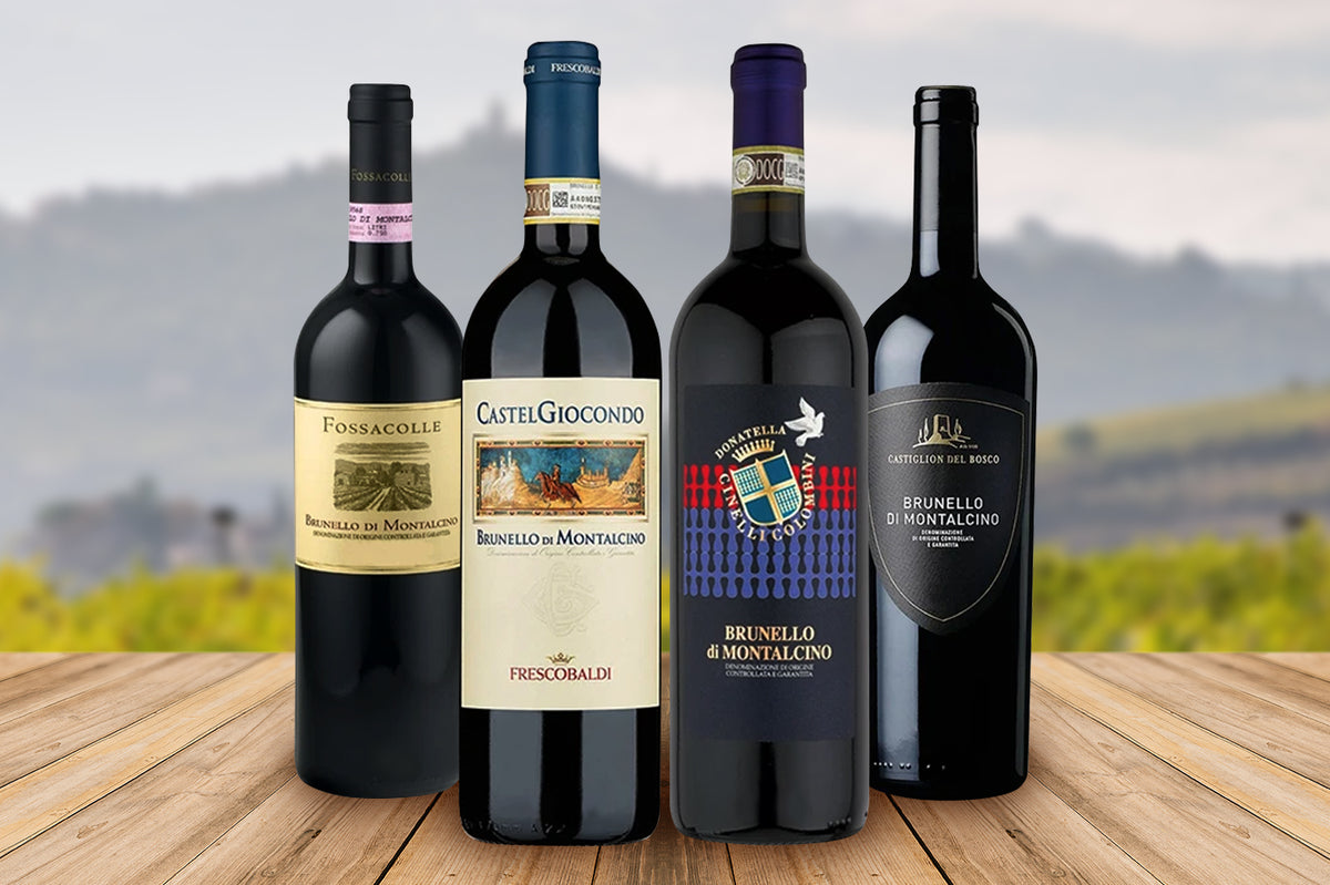 Four bottles of Brunello di Montalcino on a wooden table with vineyards behind