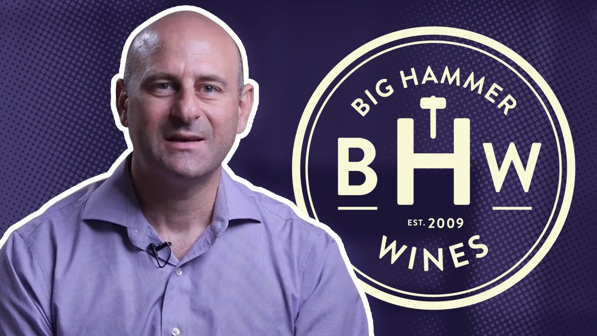 Smiling man in a lavender shirt next to the Big Hammer Wines circular logo