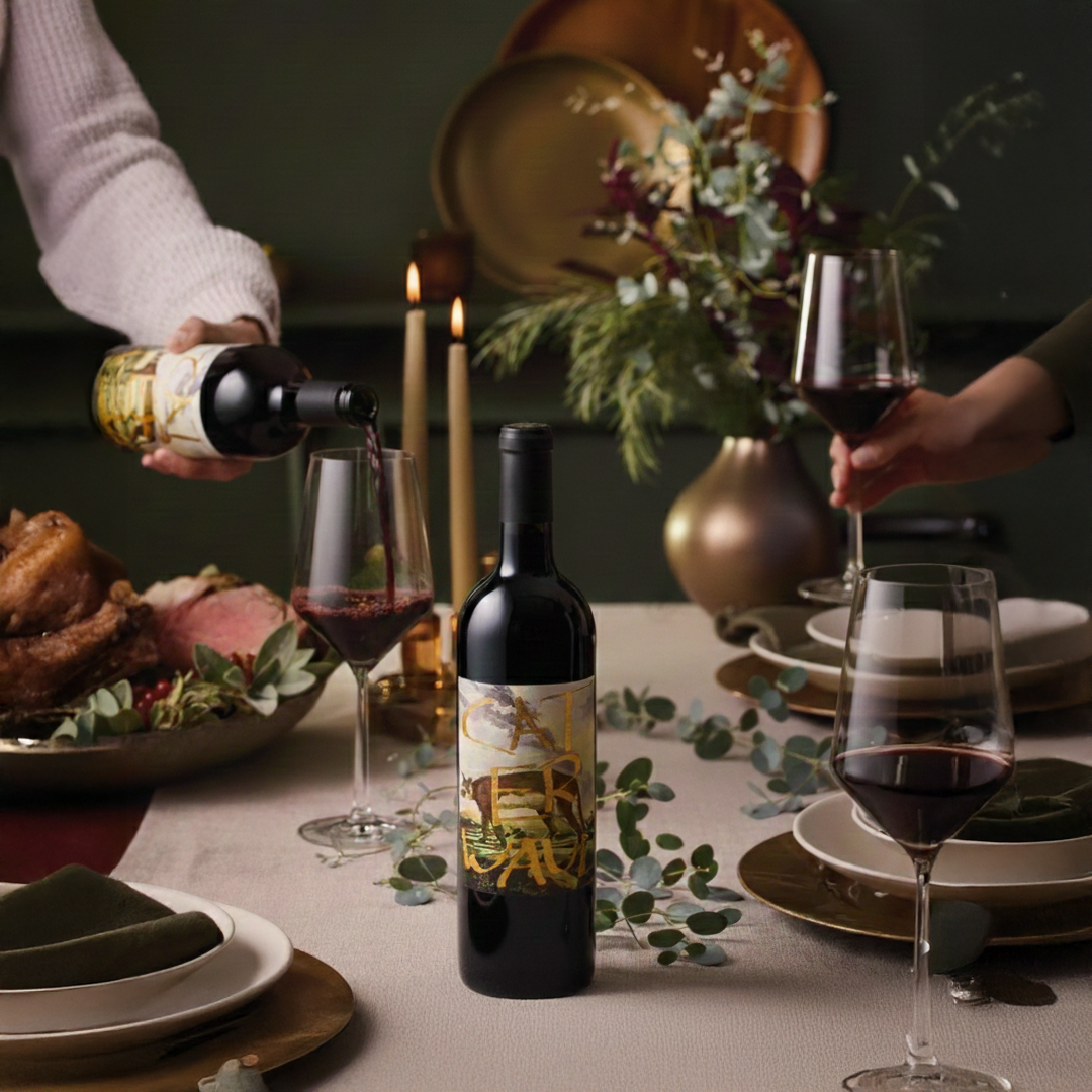 Wine being poured into glasses on a dinner table with a bottle and glasses in the foreground.