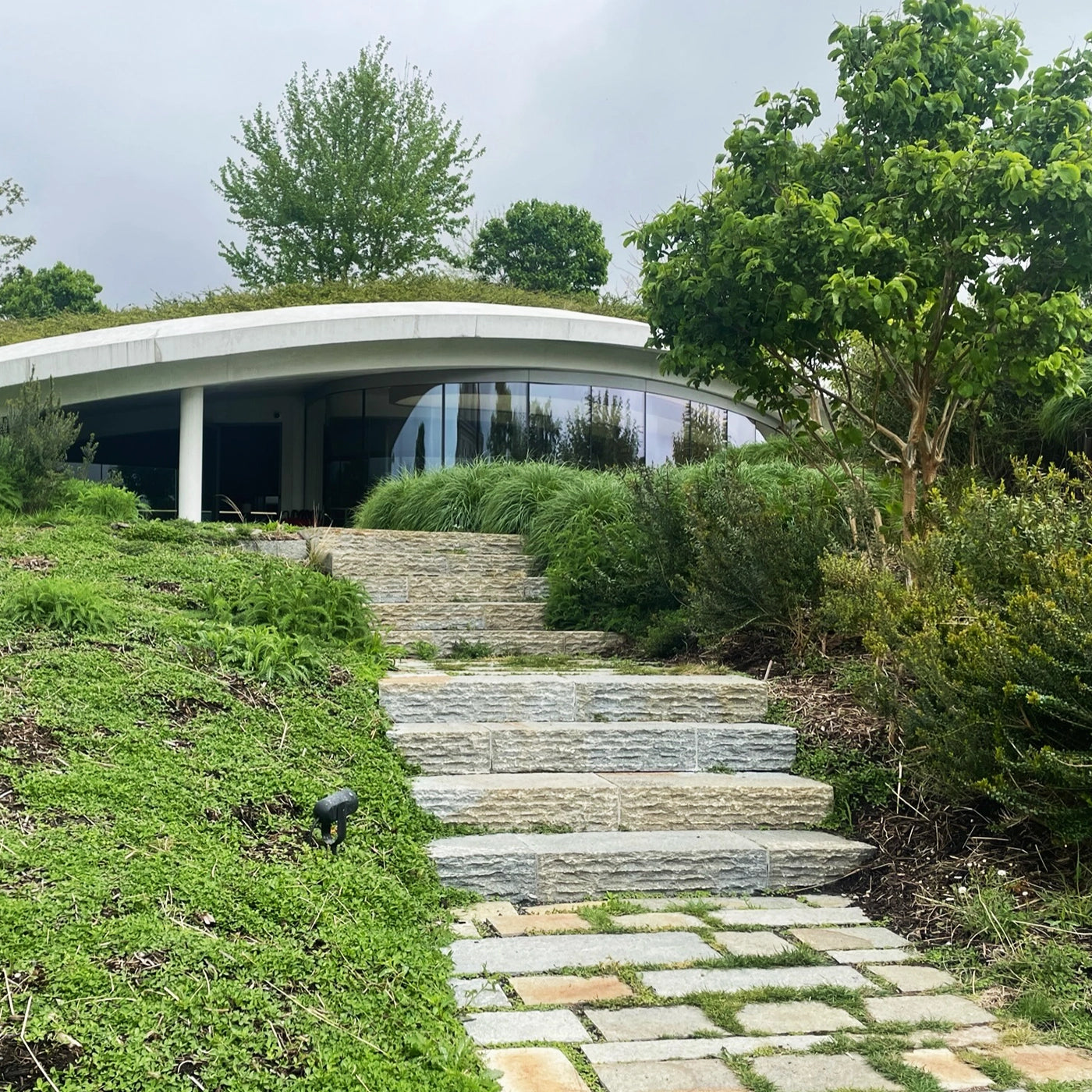 Contemporary entrance to Château Haut-Bailly winery with a green-roofed, curved building and lush landscaped surroundings, showcasing the winery’s modern design