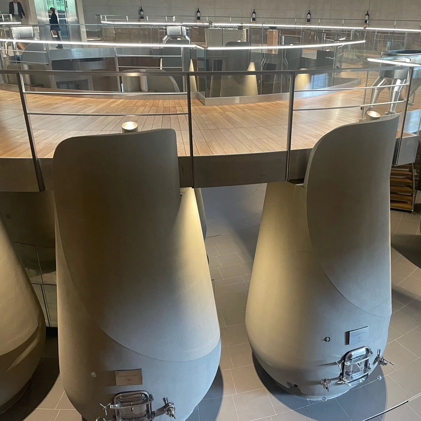 Inside the fermentation room at Château Haut-Bailly winery, showcasing large concrete fermentation tanks with a stylish mezzanine walkway above