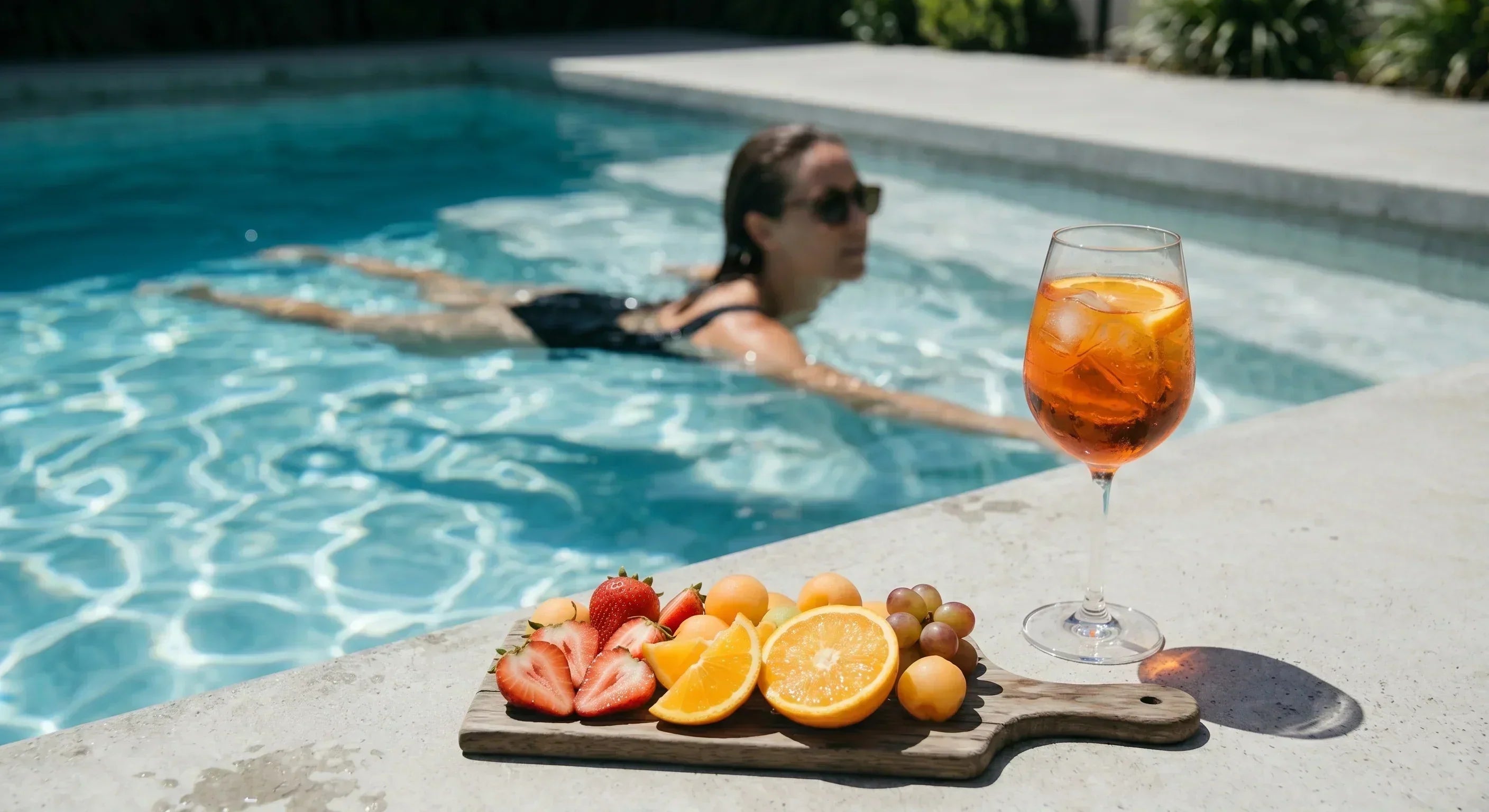 Orange wine cocktail served poolside with fresh citrus and summer fruit on a sunny afternoon