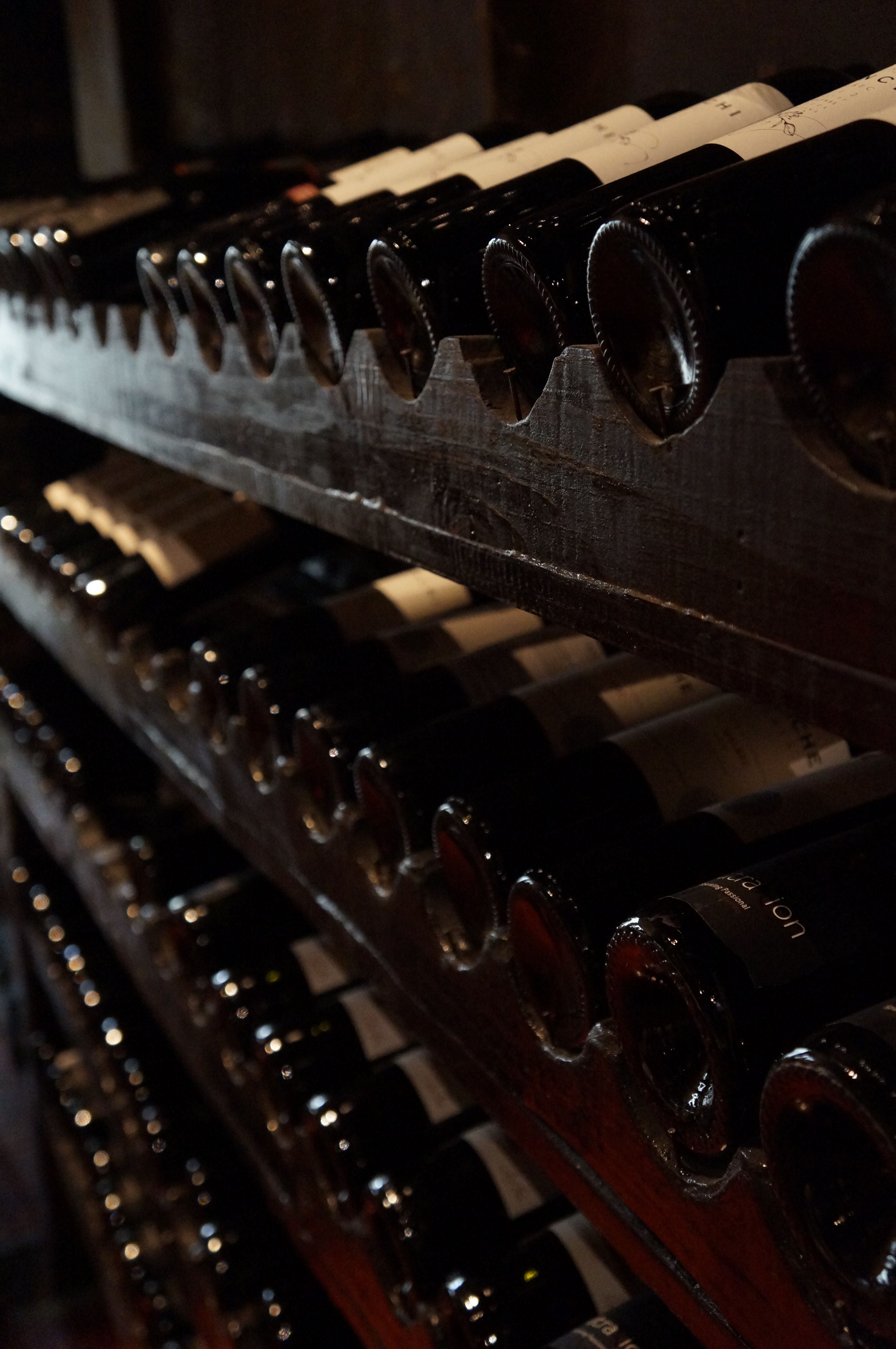 Private wine cellar with rows of aged bottles resting on dark racks