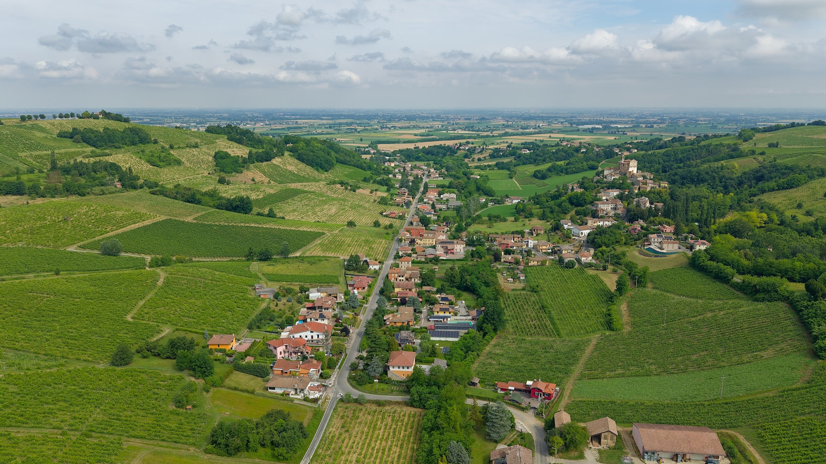 Aerial view of a village among the vineyard hills of Oltrepo Pavese above the Po plain, Lombardy, Italy