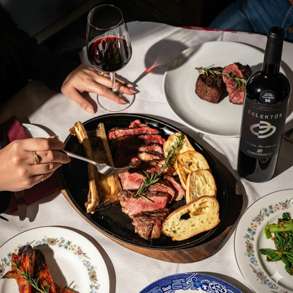 Dinner scene with steak, bread, and wine at a table.
