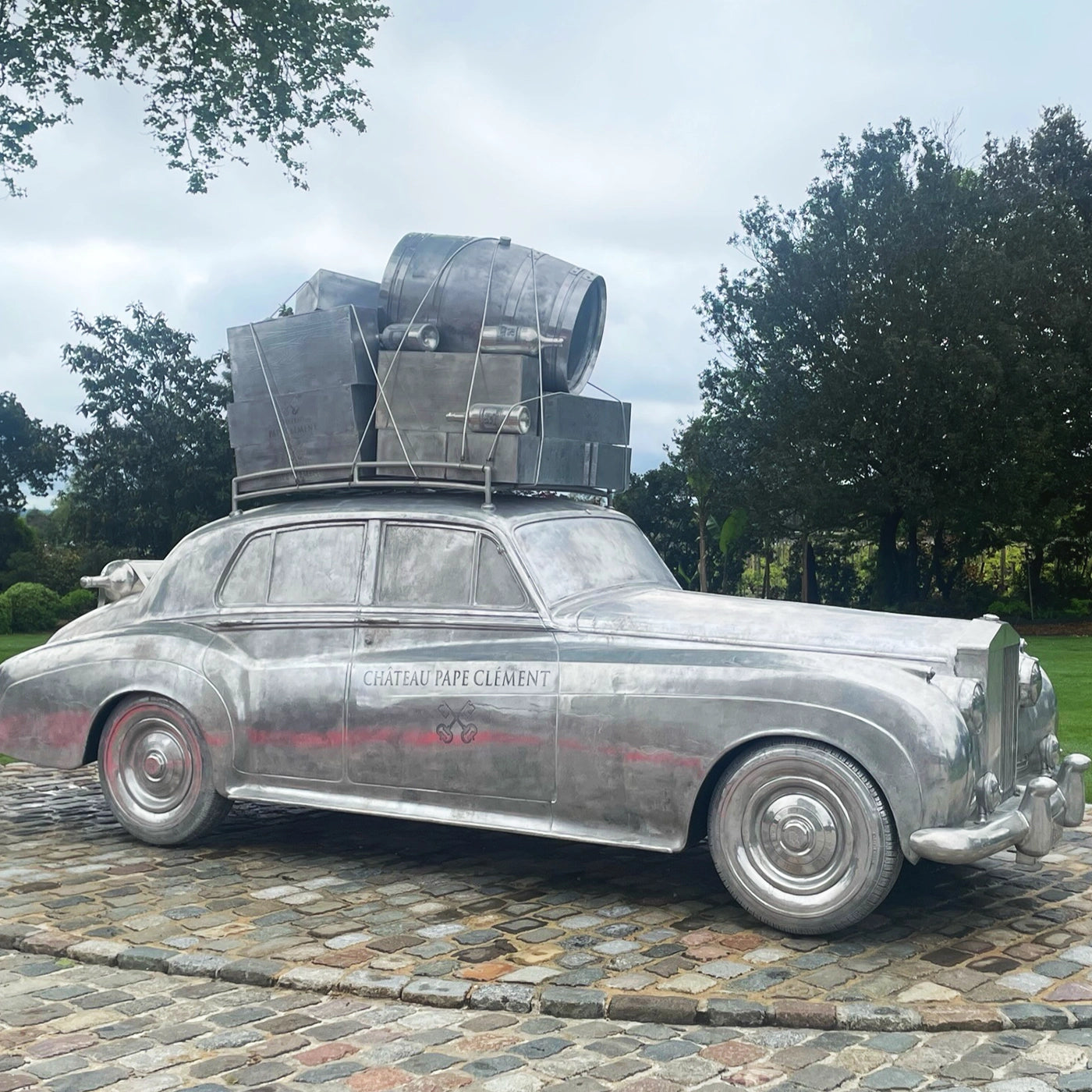 Art installation at Château Pape Clément winery, showcasing a classic car sculpture adorned with wine barrels and luggage, celebrating the winery’s prestigious history and connection to luxury