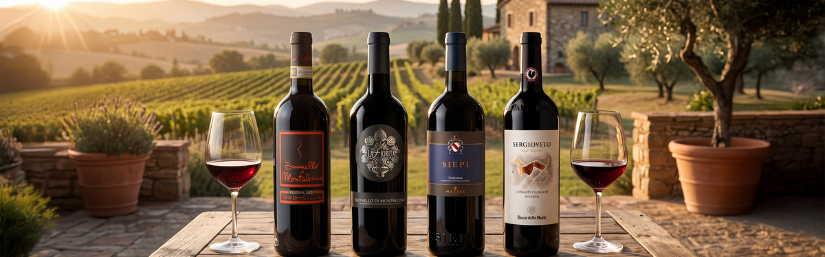 Four bottles of Sangiovese red wine with two glasses on an outdoor wooden table in Tuscany at sunset.