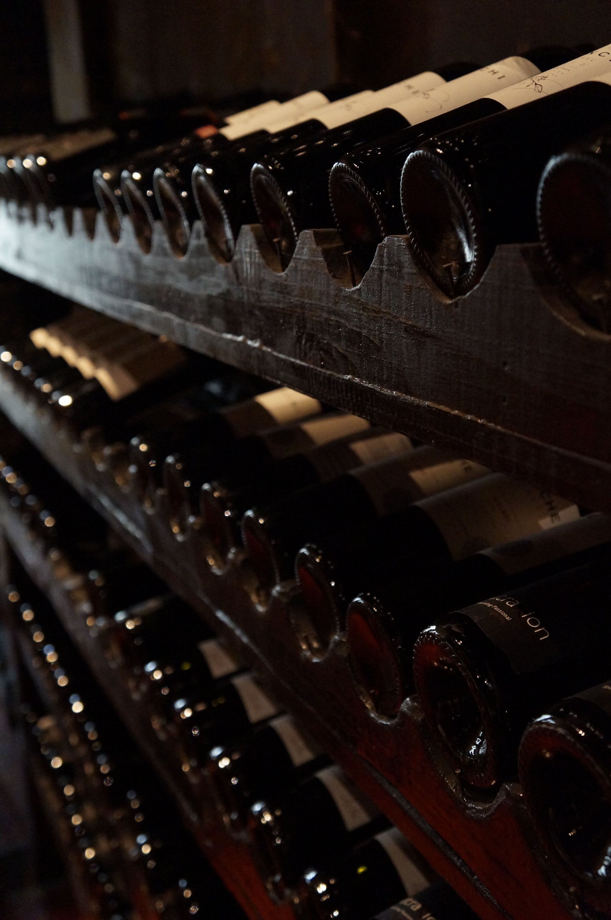 Private wine cellar with rows of aged bottles resting on dark racks